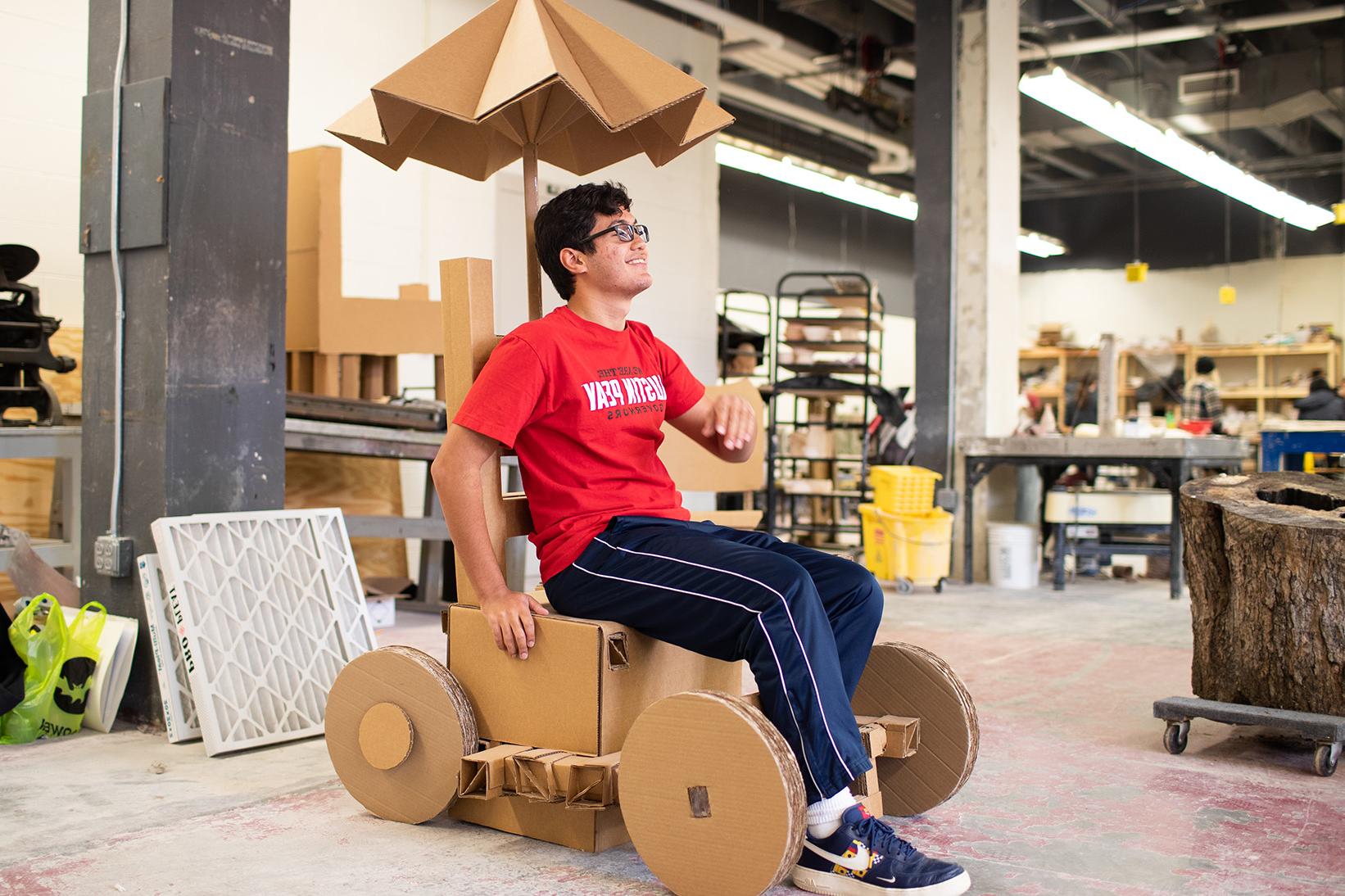 Jeremy Vega poses with his cardboard car